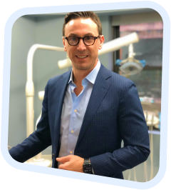 a close up of a man in a suit and glasses standing in a dentist ' s chair