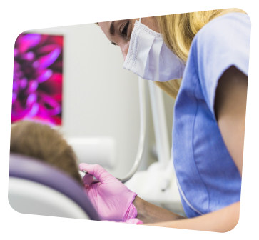 a woman in a blue shirt is getting her teeth brushed