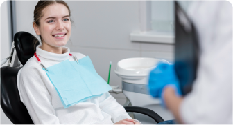 smiling woman in dental chair with blue towel and blue gloves