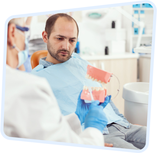 a man sitting in a chair with a model of a tooth