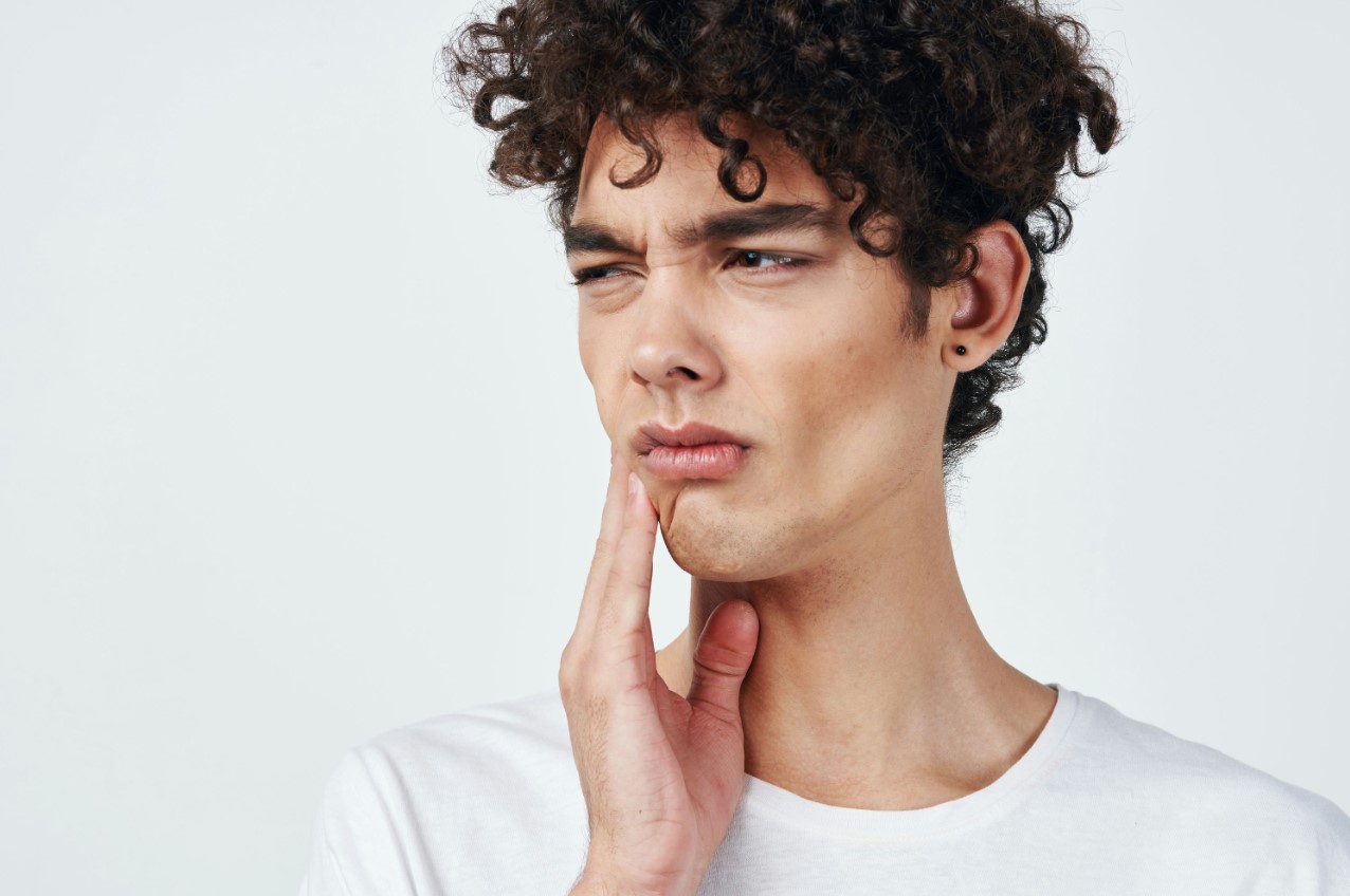 arafed man with curly hair and white shirt holding his hand to his chin