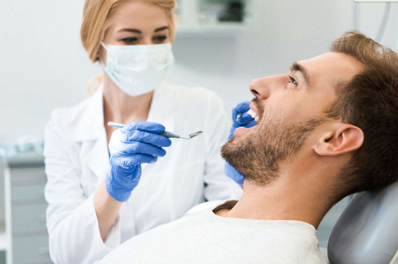 arafed man in a dentist chair with a dentist in a mask and gloves