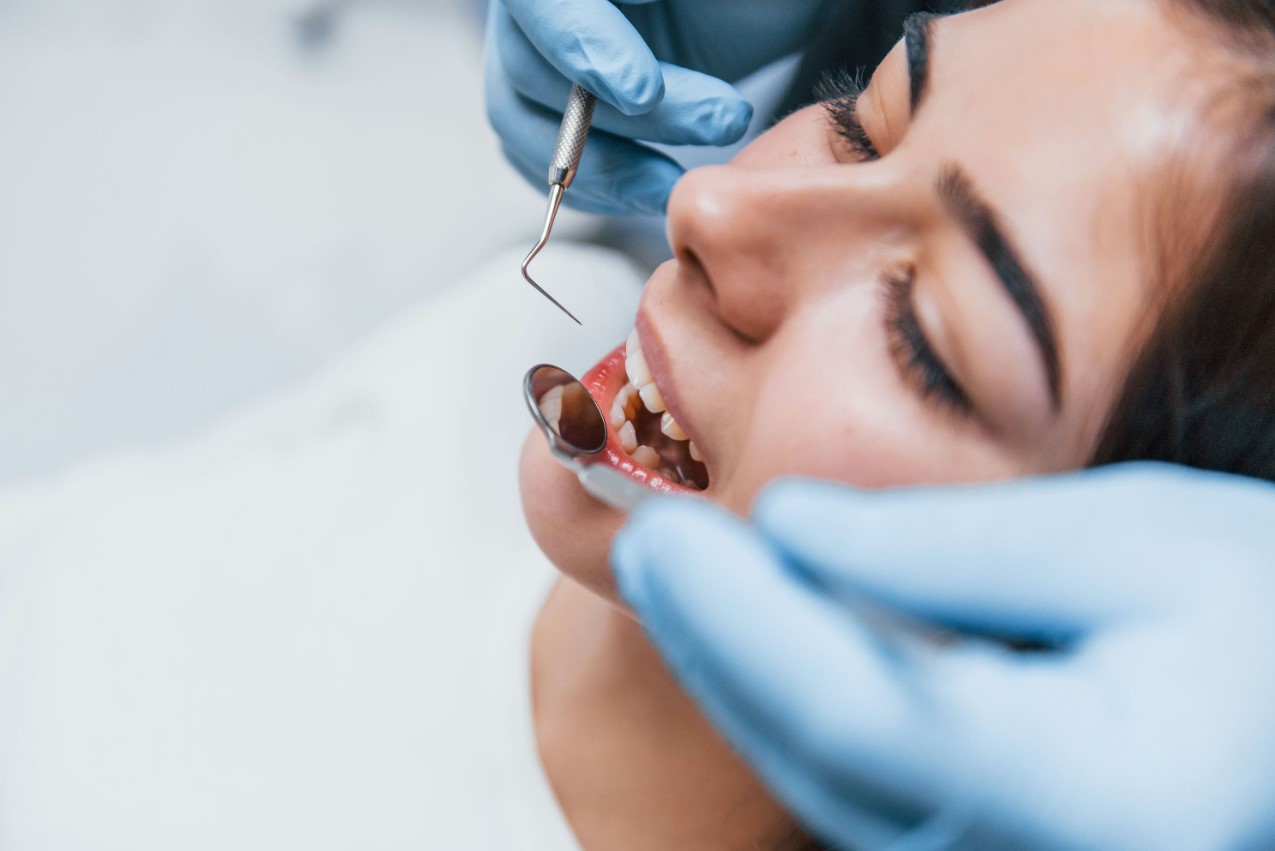 arafed woman getting her teeth brushed by a dentist